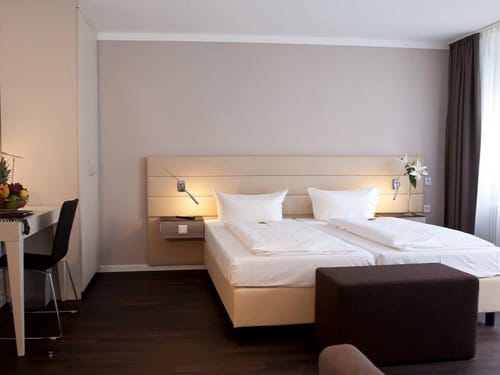 Standard Doppelzimmer mit Doppelbett, Hocker, Stuhl und Schreibtisch