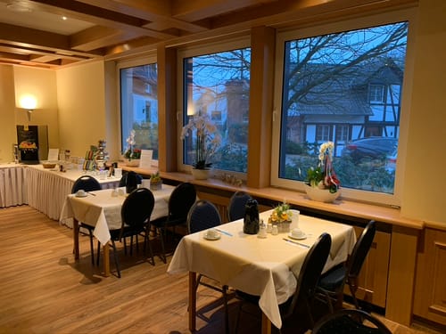 Frühstücksraum mit gedeckten Tischen und Speisenbuffet