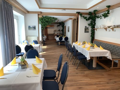 Hotel Restaurant mit weißen Tischdecken, gelben Servietten und blauen Stuhlbezügen
