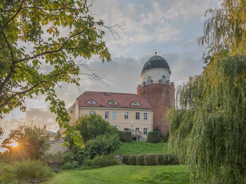 Historisches Gebäude bei Sonnenuntergang, umgeben von Bäumen