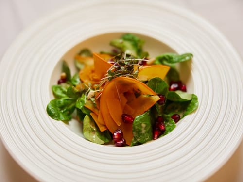 Frischer Salat mit Persimonen und Granatapfelkernen