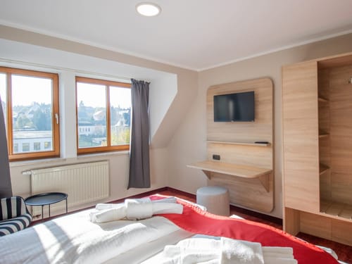 Modernes Hotelzimmer mit Doppelbett, großen Fenstern und TV