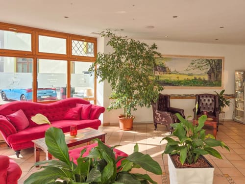 Elegante Hotellobby mit roten Sofas und grünen Pflanzen