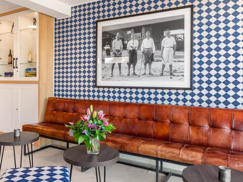Lounge mit Ledercouch, kleinen Tischen, Sesseln und Vitrine