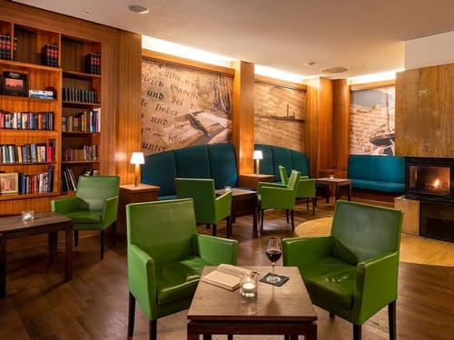 Bibliothek mit vielen Büchern, Sitzmöglichkeiten und einem Kamin