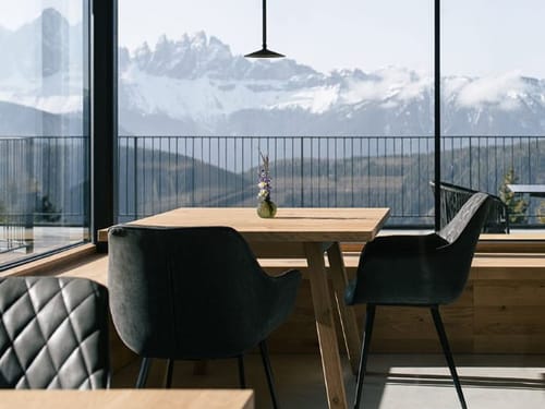 Stube mit Tischen , Stühlen und Blick auf die Berge