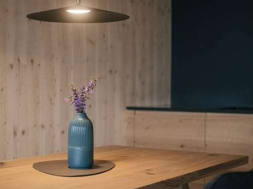 Tisch mit Vase und einer Deckenlampe