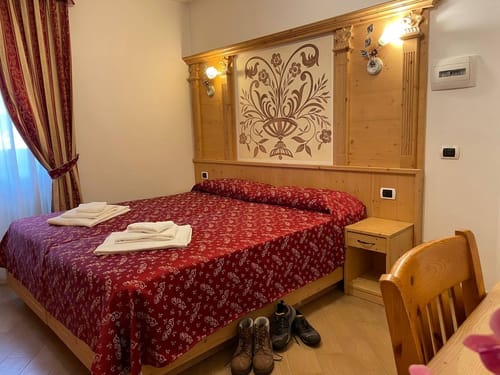 Gemütliches Hotelzimmer mit Holzmöbeln und rotem Bettbezug.