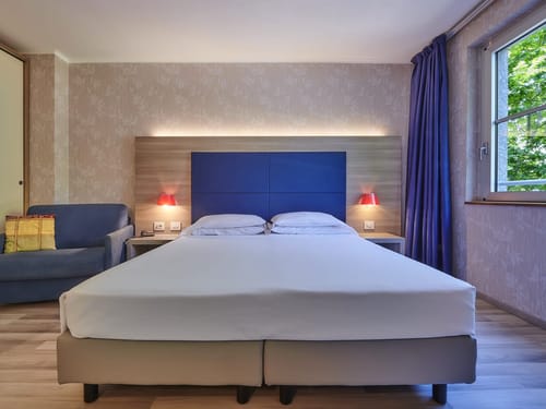 modernes Doppelzimmer mit Boxspringbett, Sessel und Leselampen
