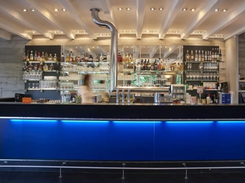 Stylische Cocktailbar mit blauer Theke und umfangreichem Spirituosenangebot