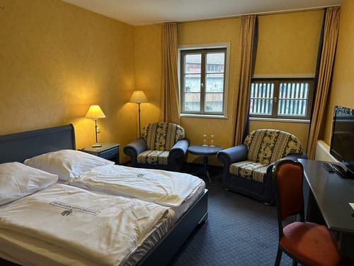 Gemütliches Doppelzimmer im Wasserschloss Westerburg mit klassischer Einrichtung, goldenen Wandfarben und historischen Sprossenfenstern