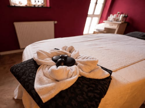 Einladende Massageliege mit Hot Stones und Handtuchblume