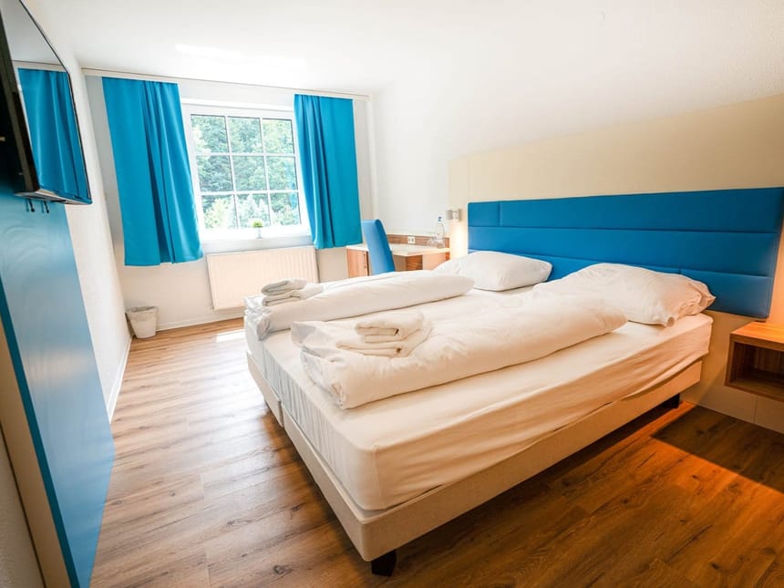 modernes Doppelzimmer mit Doppelbett, Schreibtisch, Stuhl und TV