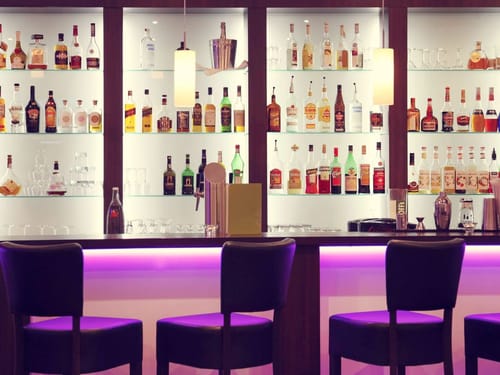 Bar mit lila LED Beleuchtung und Barhockern