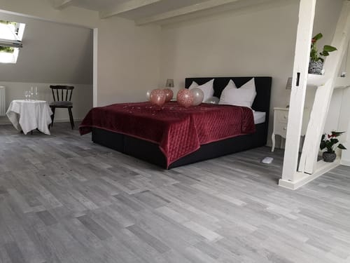 Boxspringbett mit Luftballons dekoriert und Tisch mit weißer Tischdecke und Weingläser