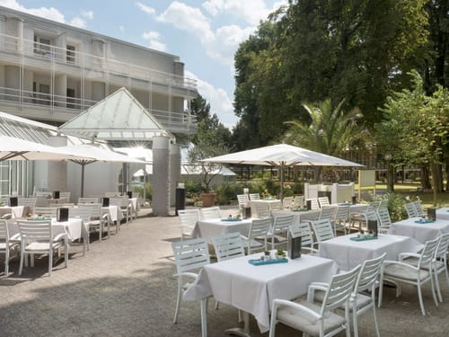 Hotelterrasse mit Sonnenschirmen, Tischen und Stühlen