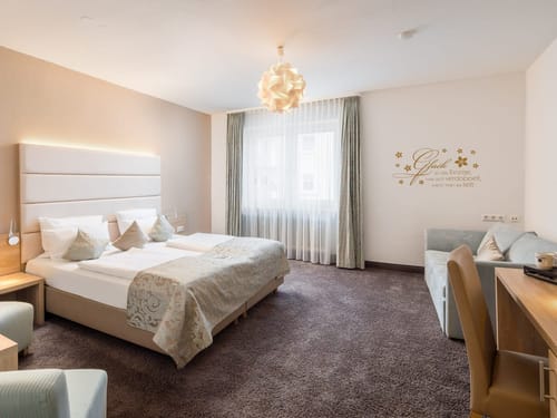 Boxspringbett, Sessel. Tisch, kleine Couch und Schreibtisch im Doppelzimmer