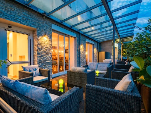 überdachte Hotelterrasse mit verschiednen Loungmöbeln am Abend