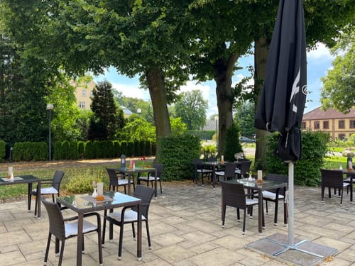Terrasse mit Tischen, Stühlen und Sonnenschirmen