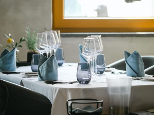 gedeckter Tisch mit weißen Tischdecken, Stoffservietten und Weingläsern