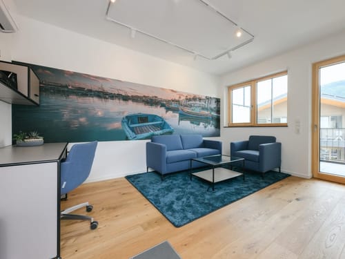geräumiger Wohnbereich mit Sessel, Couch, Tisch, Sideboard und Schreibtisch
