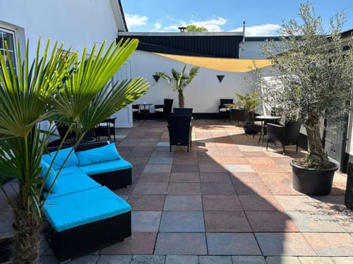 Sonnige Terrasse mit Palmen und Lounge-Möbeln