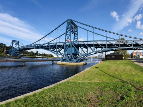 Blaue Stahlbrücke über einem Kanal bei strahlend blauem Himmel