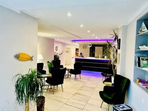 Elegante Hotel-Lounge mit moderner Inneneinrichtung und beleuchtetem Empfangstresen.