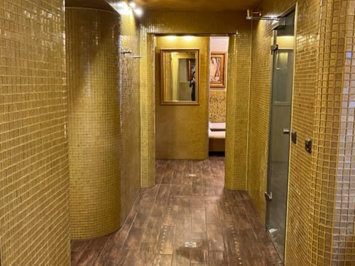 Luxuriöser Spa-Bereich mit goldenen Mosaikfliesen und Holzboden.