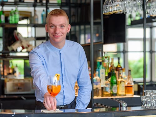 Junger Mann mit einem Cocktail in der Hand