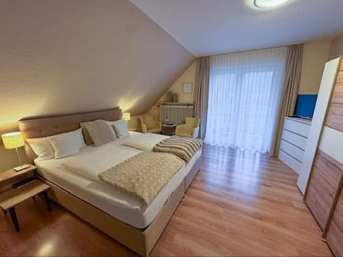 Zweibettzimmer mit TV, Tisch und Stühlen