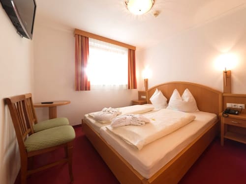 Zimmer mit TV, Tisch und zwei Stühlen