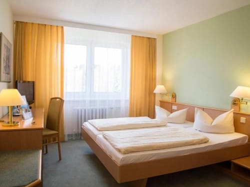 Helles Doppelzimmer mit TV, Schreibtisch und einem Stuhl