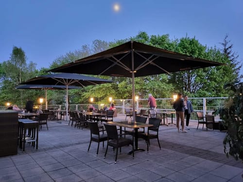 Hotelterrasse am Abend mit verschiedene Tischgruppen und Sonnenschirmen