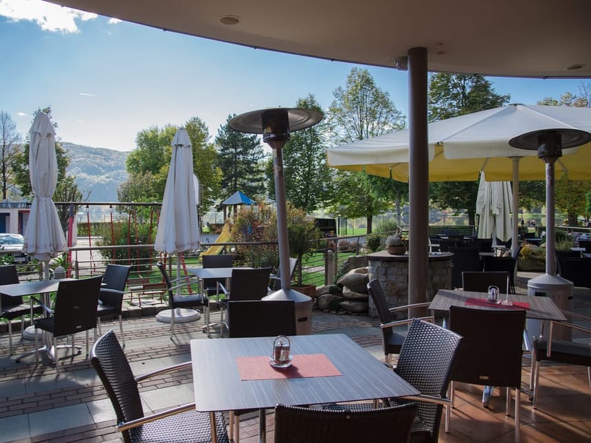 Stilvolle Restaurantterrasse mit Heizstrahlern und traumhaftem Blick in die grüne Landschaft und Berge