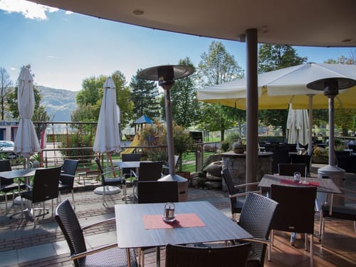 Stilvolle Restaurantterrasse mit Heizstrahlern und traumhaftem Blick in die grüne Landschaft und Berge