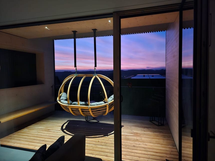 Exklusive Hängeschaukel auf Designterrasse mit Abendhimmel und Bergpanorama