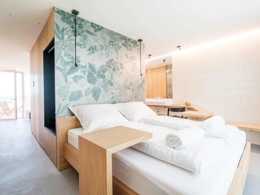 Elegantes Doppelzimmer mit floralem Wanddesign, Holzbett und offenem Badbereich