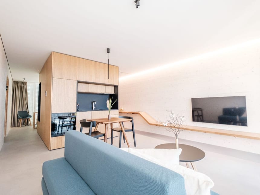 Offenes Wohn- und Küchenkonzept mit hellem Holz, blauem Sofa und modernem Essbereich in einem stilvollen Apartment