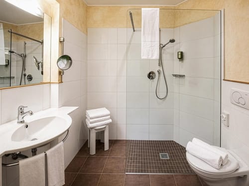 Komfortables Badezimmer im Hotel mit bodengleicher Dusche, Glasabtrennung und frischen Handtüchern