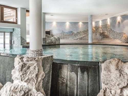 Einladender Innenpool mit beeindruckender Natursteingestaltung und stimmungsvoller Beleuchtung im Wellnessbereich