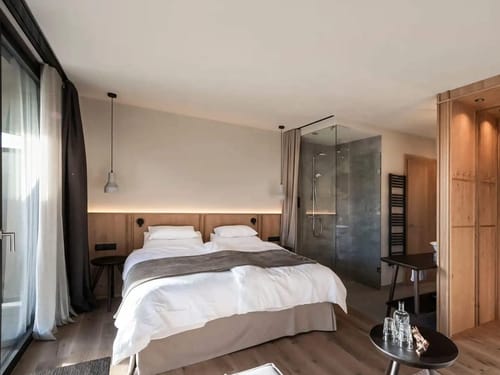 modernes Panorama Zimmer mit Boxspringbett, kleinem Wohnbreich und begehbarem Bad