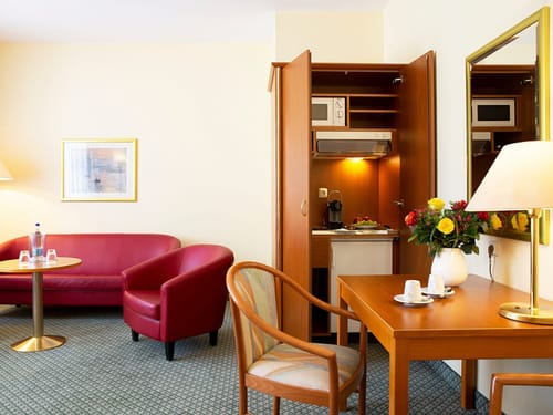 kleine rote Sitzgruppe, ein Schrank mit Miniküche, zwei Stühle und Tisch im Doppelzimmer