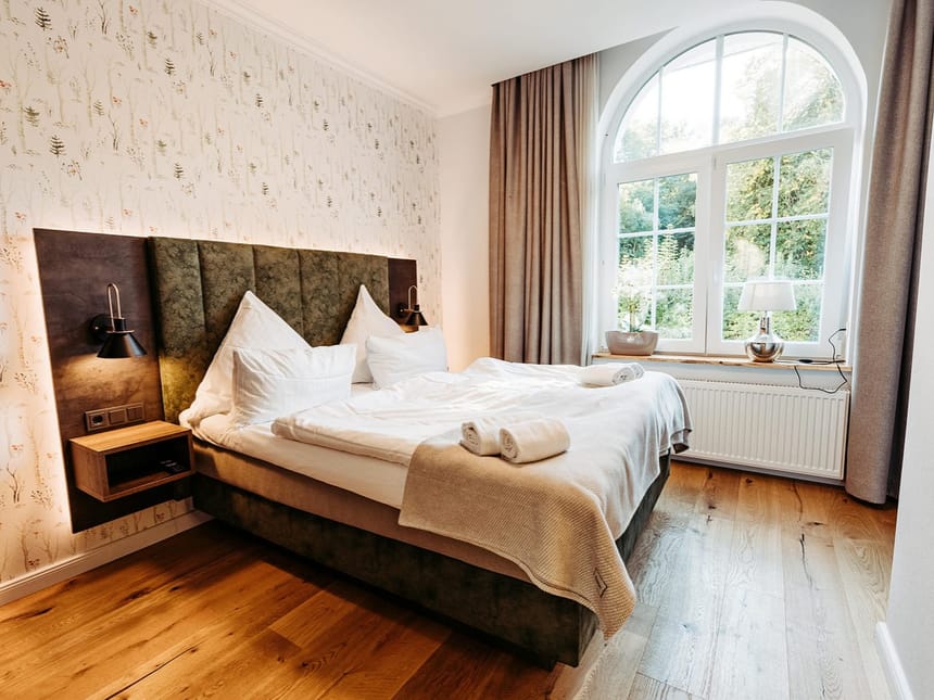 gemütliches Doppelzimmer mit Boxspringbett, Sideboard und großem Panoramafenster