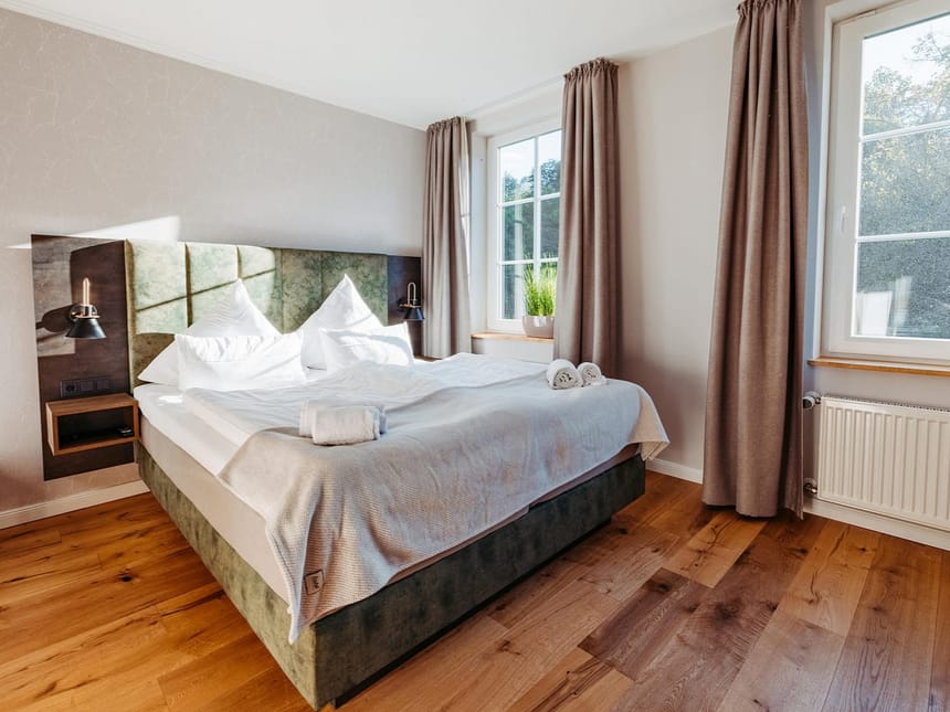 geräumiges Doppelzimmer mit Boxspringbett, Sideboard und großen Panoramafenstern