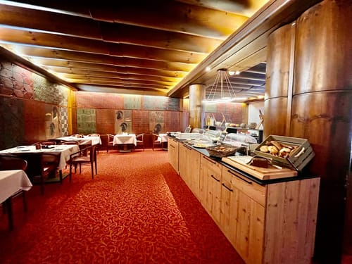 Speisenbuffet am Morgen mit verschiedenen Tischgruppen im Saal
