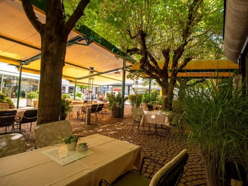 überdachte Hotelterrasse mit verschiedenen Tischgruppen