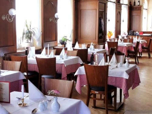 Hotelrestaurant mit verschiedenen Tischgruppen in weiß eingedeckt