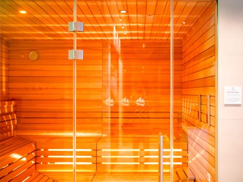 Moderne finnische Sauna mit Holzbänken und Glasfront