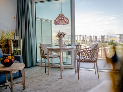 Gemütliche Essecke mit Tisch und Stühlen am Fenster mit Blick auf den Balkon.
